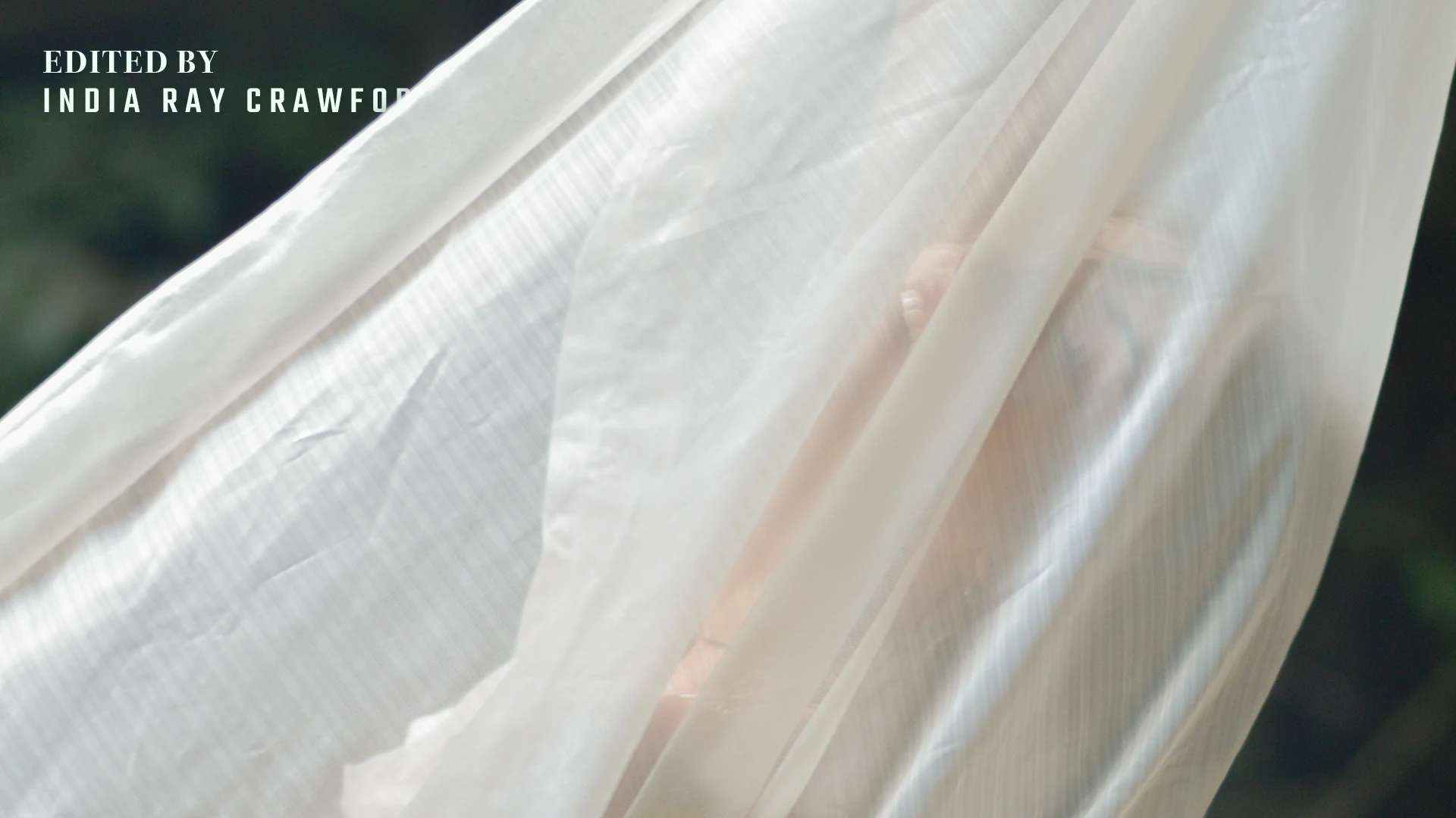 Light filtering through flowing fabric with an editing credit